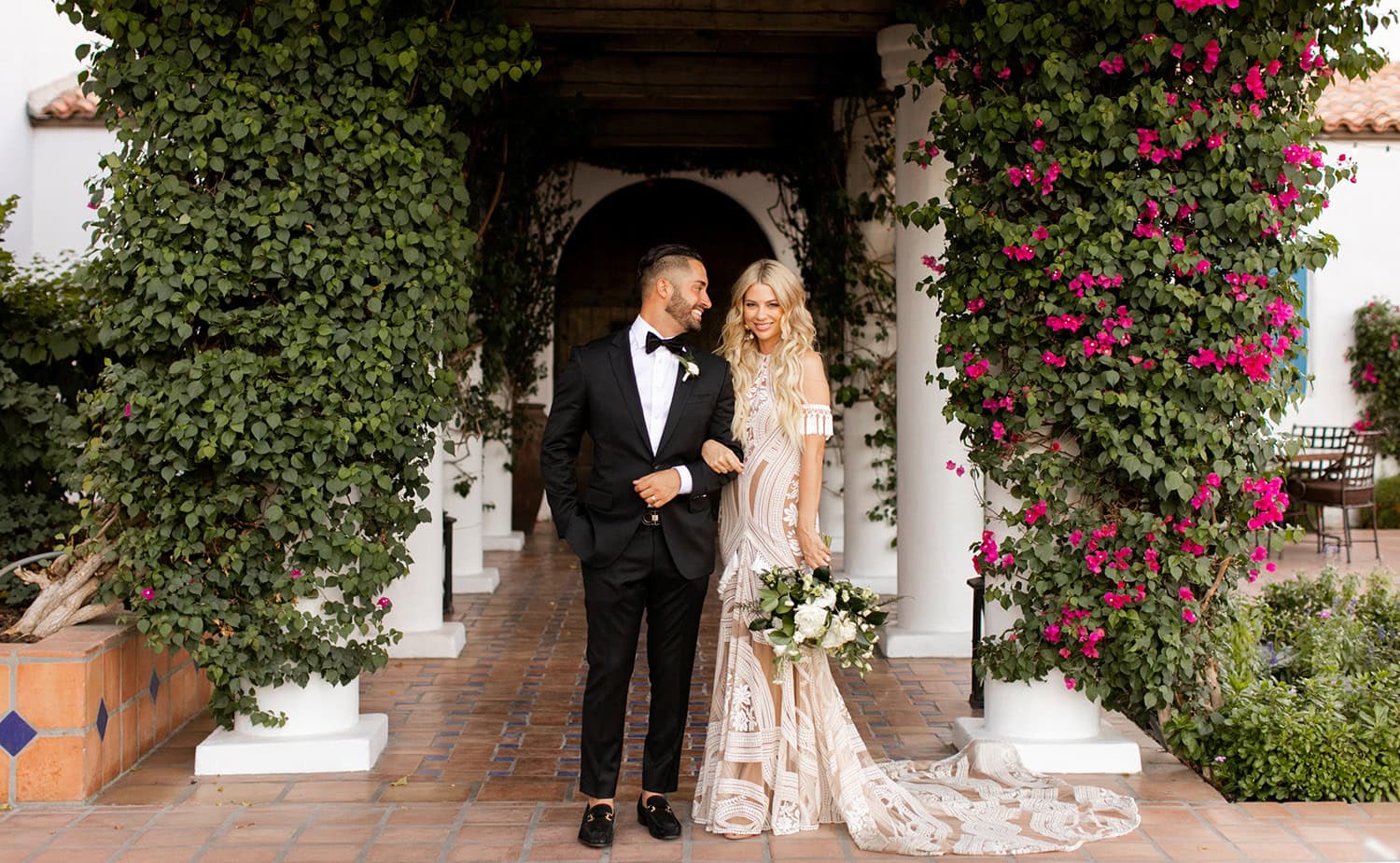 Elegant wedding couple at La Quinta Resort & Club under floral archway.