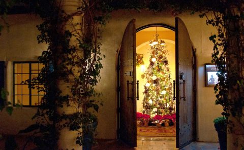 Brightly decorated Christmas tree visible through open wooden doors at La Quinta Resort & Club.