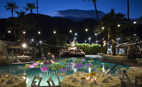 Night view of La Quinta Resort & Club with illuminated pool and floating flamingo inflatables.