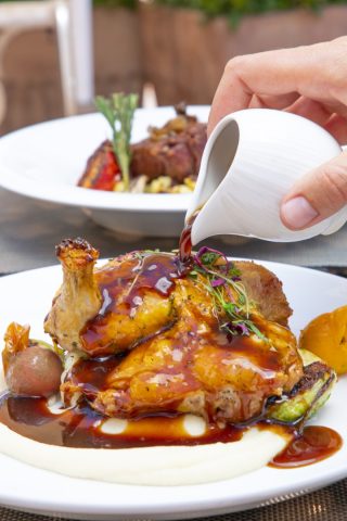 Delicious roasted chicken topped with rich sauce, served with fresh vegetables at La Quinta Resort &.