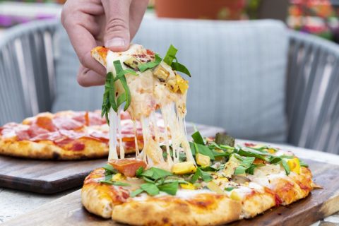 Pizza with fresh basil, vegetables, and melted cheese served at La Quinta Resort & Club.