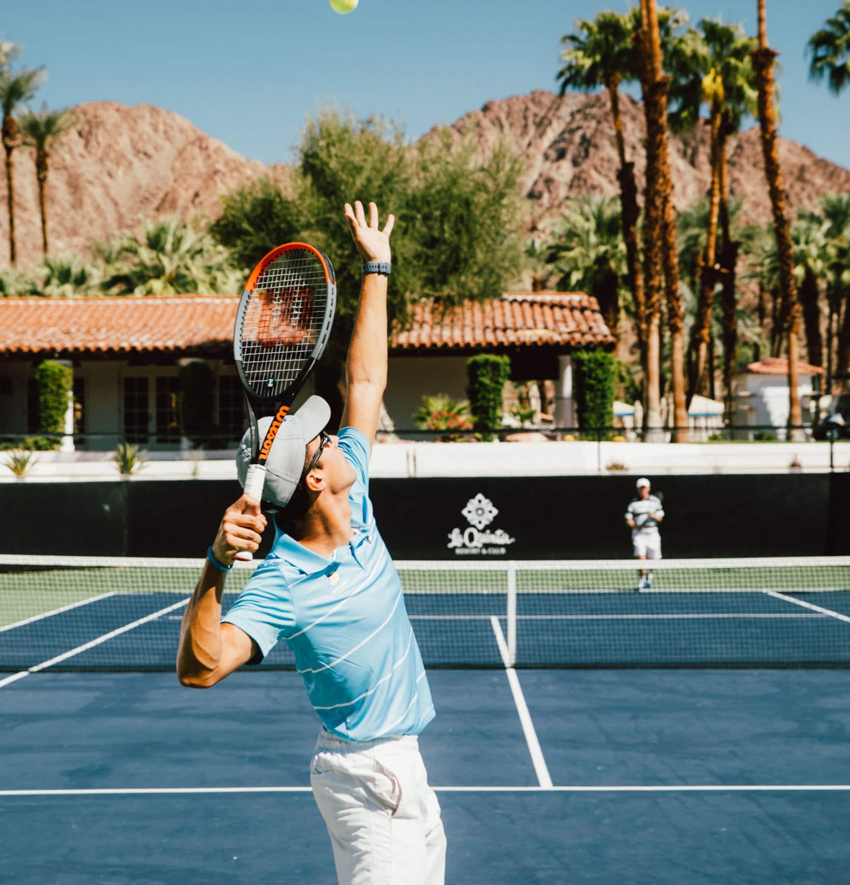 Woman playing tennis at La Quinta Resort & Club with scenic mountain backdrop.