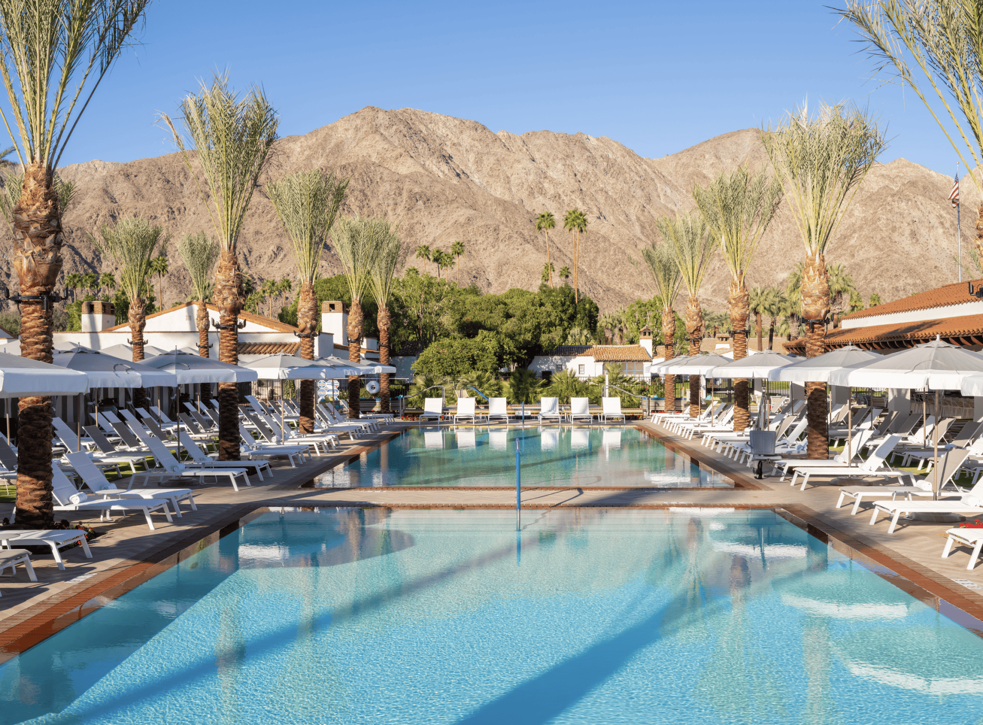 Poolside at La Quinta Resort & Club during summer. Relaxing oasis with mountain views and lush palm.