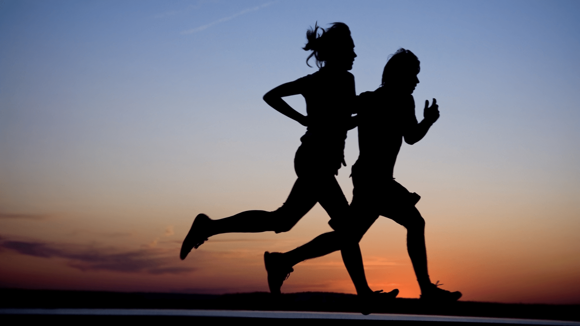 Silhouettes of two people jogging at sunset at La Quinta Resort & Club.