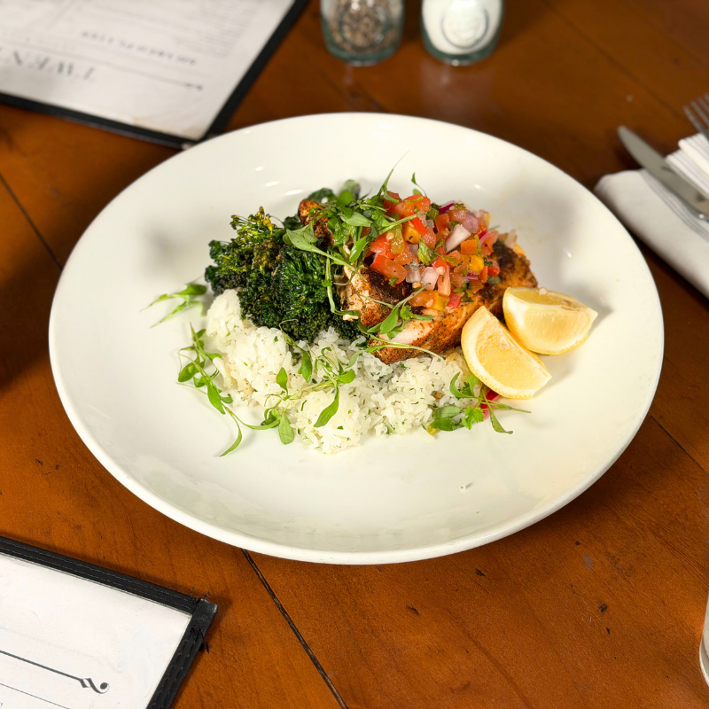 Fresh fish with vegetables and lemon wedges on a white plate at La Quinta Resort.