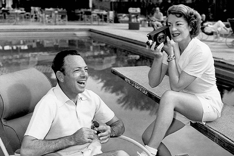 Vintage photo of a woman taking a picture of a man by the pool.