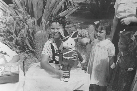 Children playing with a toy rabbit at La Quinta Resort in a vintage setting.