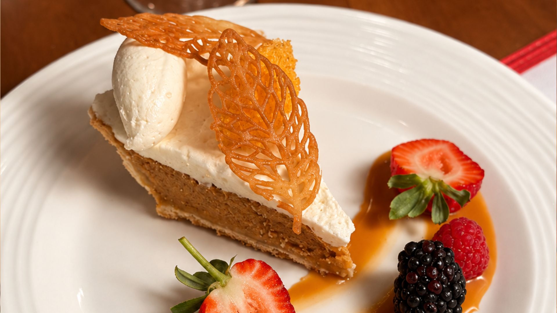 Slice of pumpkin pie with whipped cream and caramelized sugar decoration.