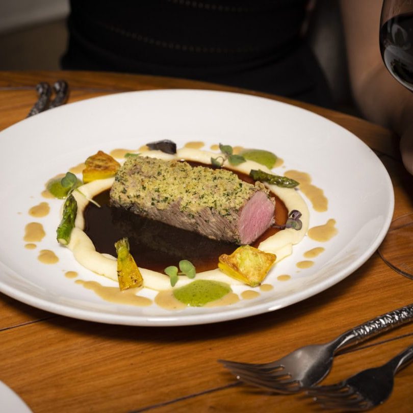 Elegant lamb chop plated with colorful vegetables and sauces at La Quinta Resort & Club.