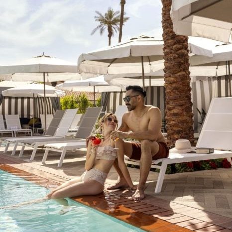 Poolside relaxation at La Quinta Resort & Club with a couple enjoying drinks under umbrellas.