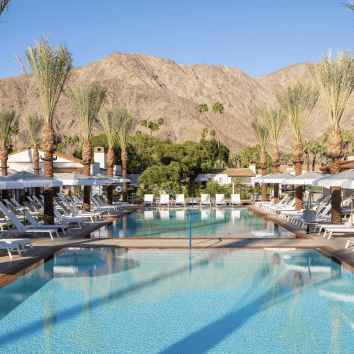 Poolside at La Quinta Resort & Club during summer. Relaxing oasis with mountain views and lush palm.